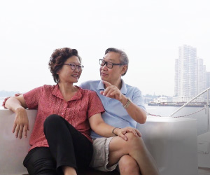 An elderly Asian couple talking while enjoying a ride on a yacht