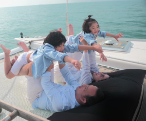 An Asian couple playing with their two children on a yacht
