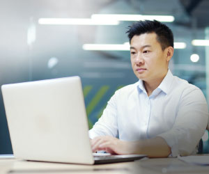 An Asian male working on his laptop