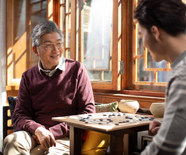 Elderly Asian father enjoying a game of GO with his son.